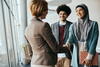 a man standing next to a woman shaking hands with another woman